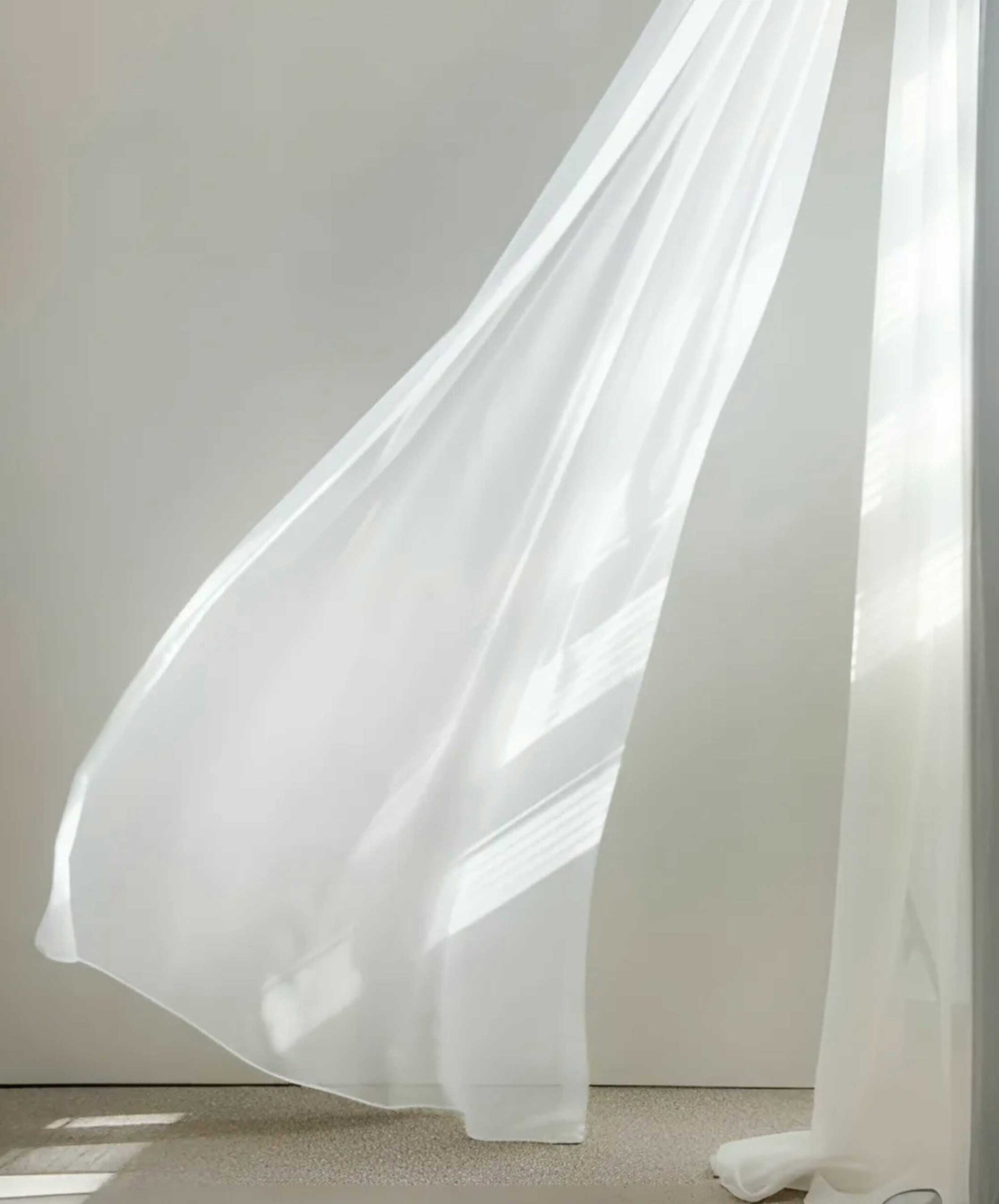 white curtain which flies in the wind in a white room